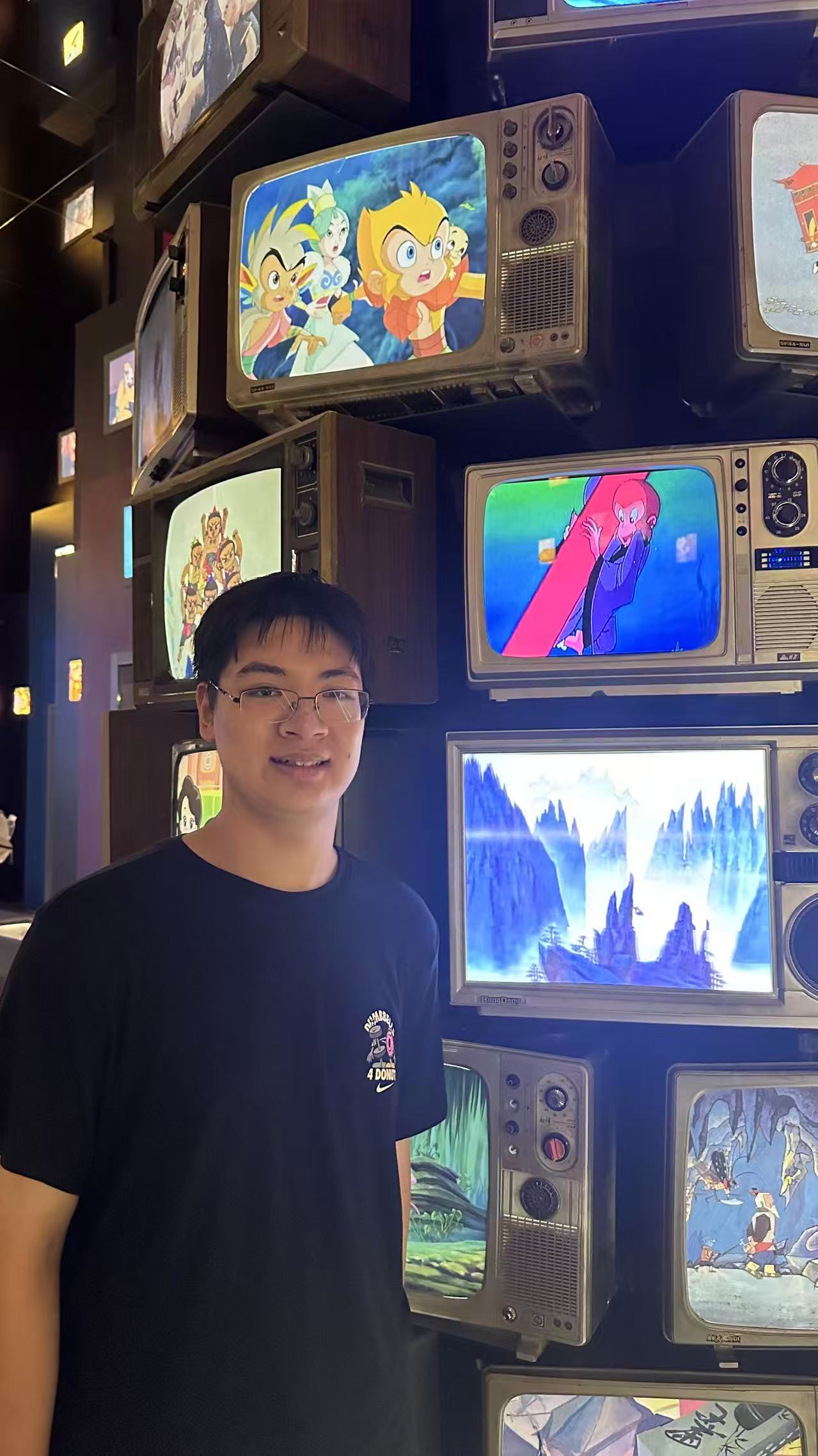 Zhang Zhenming in front of a wall of vintage television screens